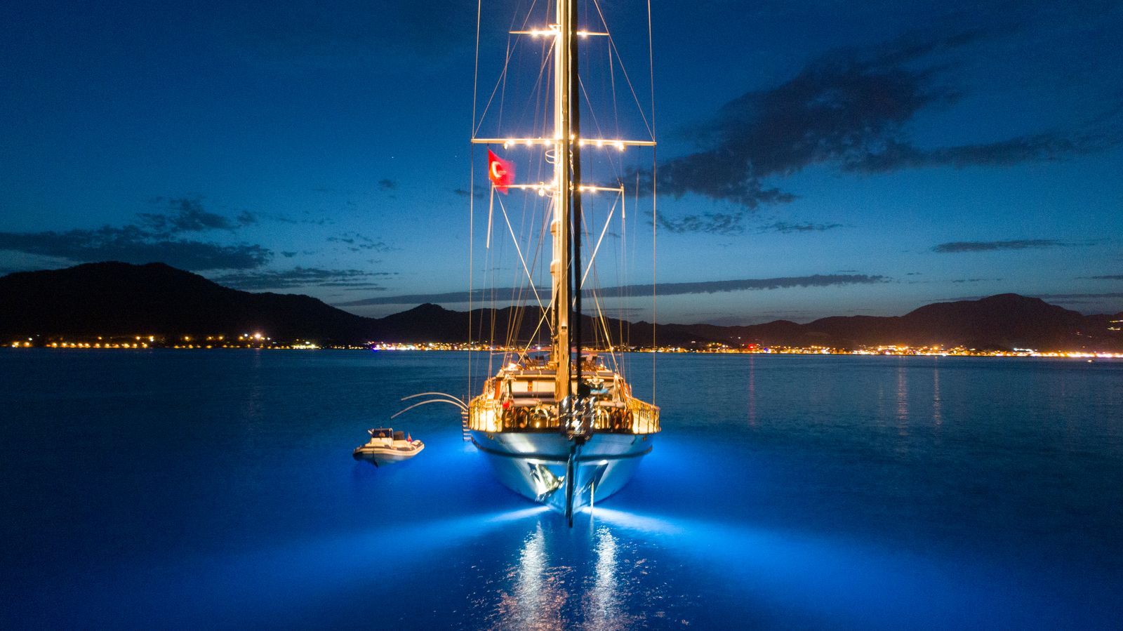 Sailing yacht at anchor at night with underwater lights